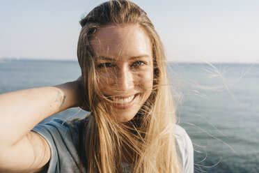 Portrait of happy young woman with blowing hair in front of the sea - KNSF00673