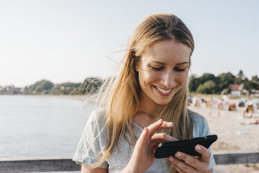 Lächelnde junge Frau mit Smartphone - KNSF00674