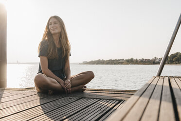 Portrait of smiling young woman relaxing on jetty - KNSF00680