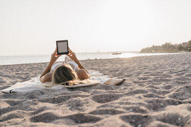 Junge Frau liegt auf einer Decke am Strand und benutzt ein Tablet - KNSF00687