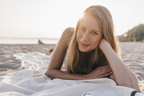 Porträt einer jungen Frau, die auf einer Decke am Strand liegt, lizenzfreies Stockfoto