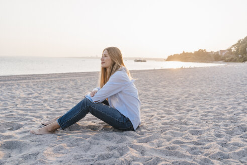 Junge Frau sitzt abends am Strand - KNSF00696