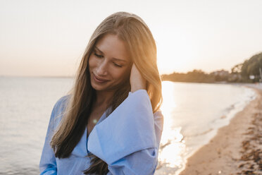 lächelnde junge Frau am Strand bei Sonnenuntergang - KNSF00700