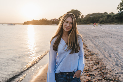 Smiling young woman on the beach at twilight stock photo