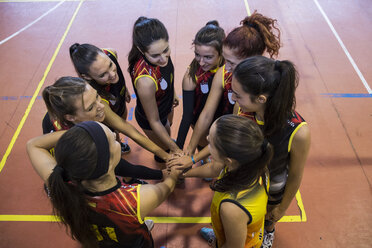 Female volleyball team huddling and stacking hands - ABZF01566