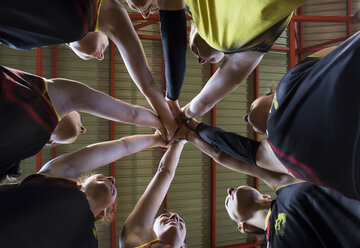 Female volleyball team huddling and stacking hands - ABZF01570