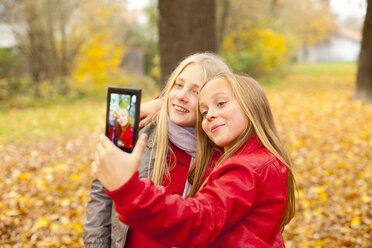 Zwei glückliche Mädchen nehmen Selfie mit Handy im Herbst - MAEF12058