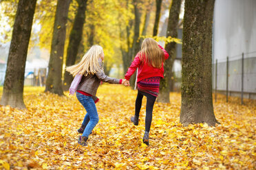 Rückenansicht von zwei springenden Mädchen im Herbst - MAEF12064
