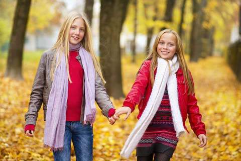 Two happy girls hand in hand in autumn stock photo