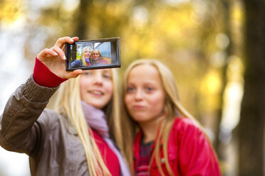 Zwei Mädchen nehmen Selfie mit Handy im Herbst - MAEF12067