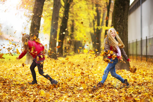 Zwei Mädchen spielen mit Herbstblättern - MAEF12069