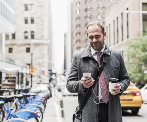 USA, New York City, businessman on the move in Manhattan looking on cell phone stock photo