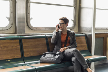 Businesswoman on a ferry on cell phone - UU09334