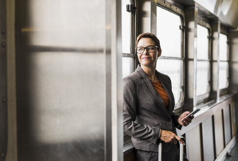 Businesswoman on a ferry looking out of window - UU09336