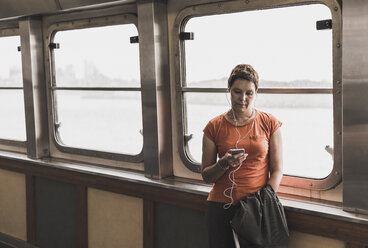 Woman on a ferry looking on cell phone - UU09348