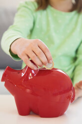 Girl putting coin into piggy bank, close-up - LVF05632