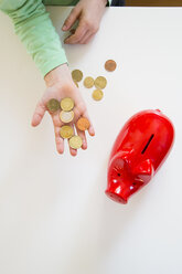 Girl's hand with coins and a red piggy bank - LVF05634