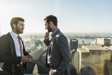 USA, New York City, two businessmen talking on Rockefeller Center observation deck - UU09357