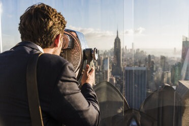 USA, New York City, Mann schaut durch ein münzbetriebenes Fernglas auf der Aussichtsplattform des Rockefeller Center - UU09358