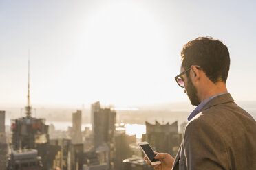 USA, New York City, Geschäftsmann mit Mobiltelefon auf der Aussichtsplattform des Rockefeller Center - UU09364