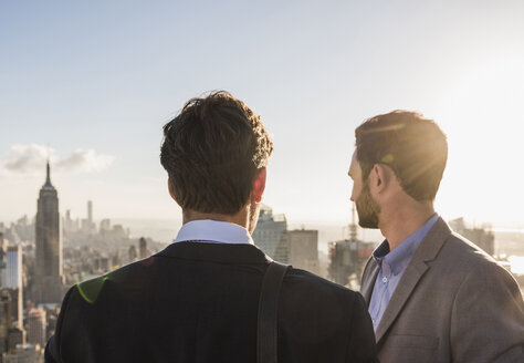 USA, New York City, two businessmen looking on cityscape on Rockefeller Center observation deck - UU09368