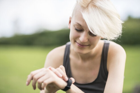 Lächelnde junge Frau überprüft ihre Smartwatch - TAMF00828