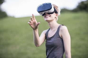 Lächelnde junge Frau mit Virtual-Reality-Brille im Freien - TAMF00833