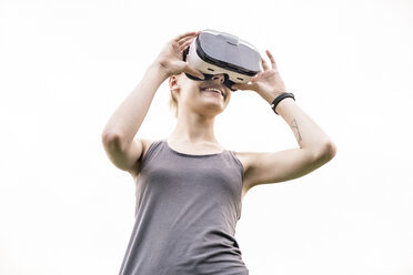 Lächelnde junge Frau mit Virtual-Reality-Brille im Freien - TAMF00836
