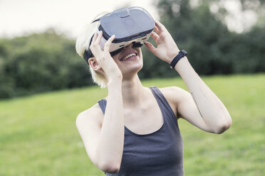 Lächelnde junge Frau mit Virtual-Reality-Brille im Freien - TAMF00837