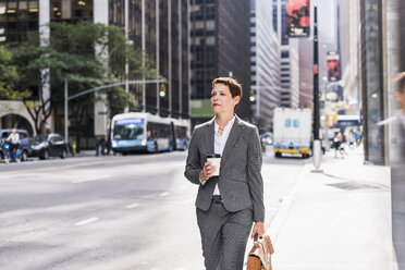 USA, New York City, Geschäftsfrau in Manhattan mit Kaffee zum Mitnehmen - UUF09384