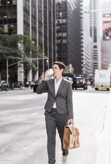 USA, New York City, Geschäftsfrau in Manhattan mit Kaffee zum Mitnehmen - UUF09386