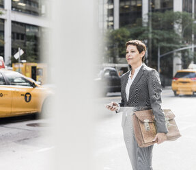 USA, New York City, Geschäftsfrau in Manhattan mit Mobiltelefon - UUF09394