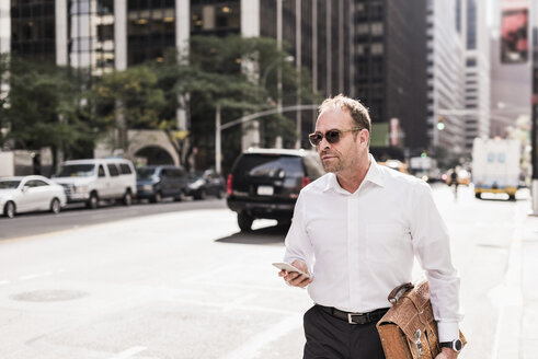 USA, New York City, businessman in Manhattan with cell phone - UUF09397