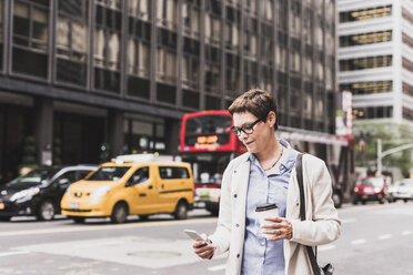 USA, New York City, Frau in Manhattan schaut auf Handy - UUF09410