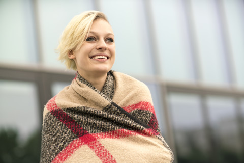 Porträt einer lächelnden, in ein Tuch gewickelten blonden Frau, lizenzfreies Stockfoto