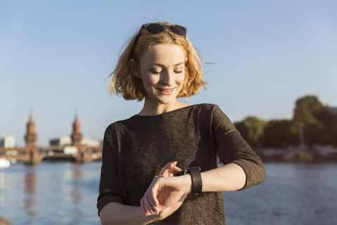 Junge Frau überprüft ihre Smartwatch, lizenzfreies Stockfoto