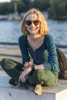Porträt einer lächelnden jungen Frau mit Sonnenbrille und Smartwatch - TAMF00863