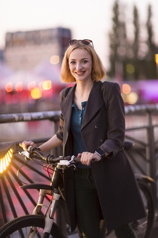 Portrait of happy young woman with bicycle at evening twilight stock photo