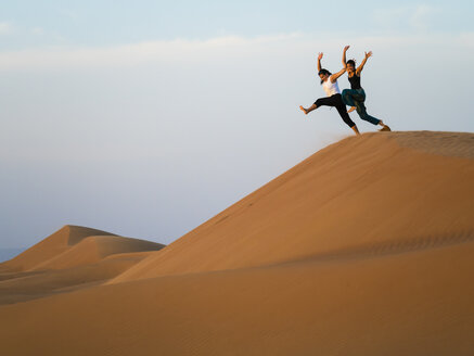 Oman, Al Raka, zwei junge Frauen springen von einer Düne in der Wüste Rimal Al Wahiba - AMF05097