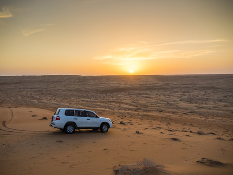Oman, Al Raka, off-road vehicle parking on dune in Rimal Al Wahiba desert at sunset stock photo