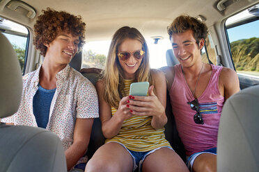 Glückliche Freunde, die im Auto ihr Handy überprüfen - WESTF21999