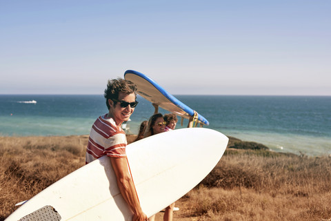 Friends carrying surfboards at the coast stock photo