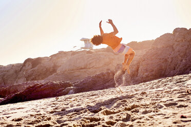 Young man on the beach doing a somersault - WESTF22028