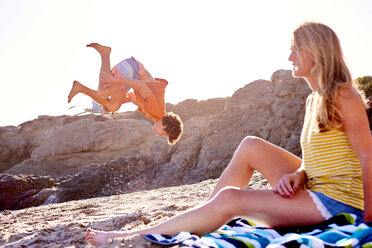 Young man with woman on the beach doing a somersault - WESTF22029