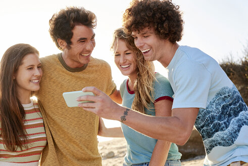 Glückliche Freunde mit Handy am Strand - WESTF22051