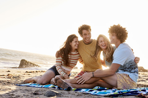 Happy friends sitting on the beach stock photo