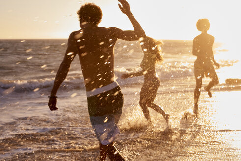 Verspielte Freunde am Strand bei Sonnenuntergang - WESTF22059