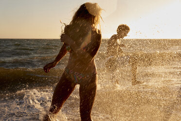 Playful couple in the sea at sunset - WESTF22060