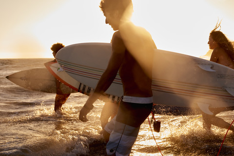 Surfer auf dem Meer bei Sonnenuntergang, lizenzfreies Stockfoto