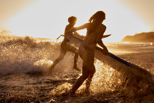 Surfer laufen bei Sonnenuntergang ins Meer - WESTF22065